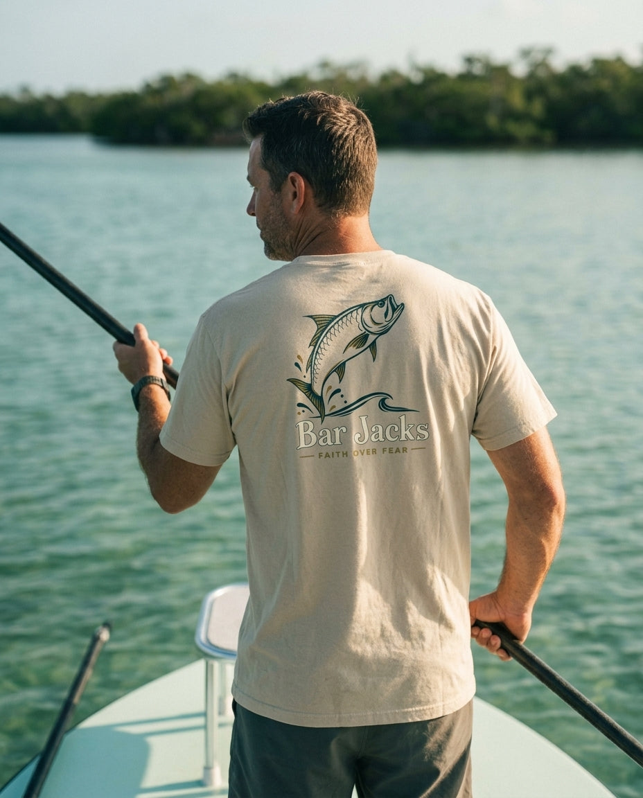 Man wearing the Bar Jacks Faith Over Fear tan cotton tee poling a flats skiff in the Florida Keys, back print visible
